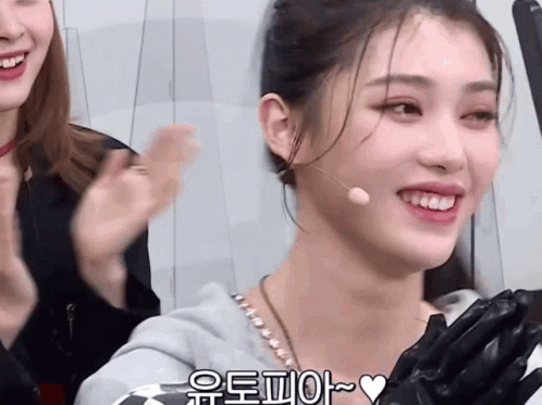 A Woman Wearing A Microphone And Gloves Is Smiling With A Heart In The Lower Right Corner GIF