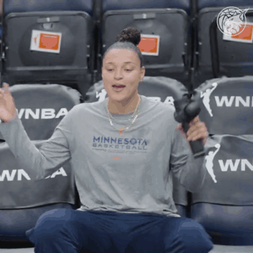 A Woman Wearing A Minnesota Basketball Shirt Is Sitting In A Stadium GIF