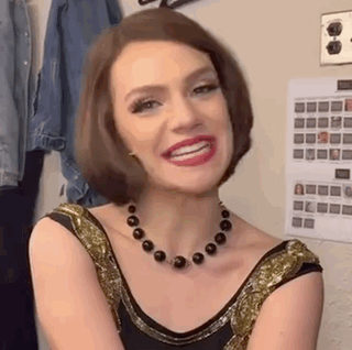 a woman wearing a necklace and a dress is smiling .