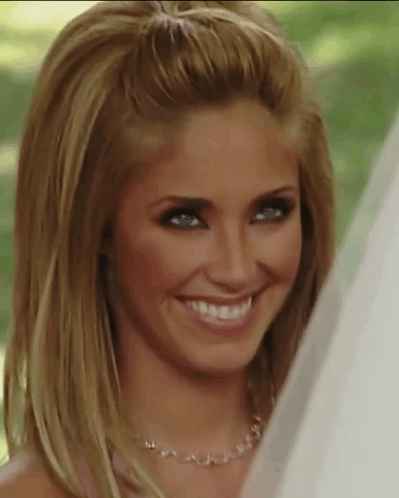 A Woman Wearing A Necklace And A Veil Smiles For The Camera GIF