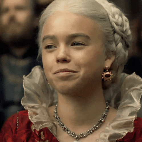 A Woman Wearing A Necklace And Earrings Is Smiling For The Camera GIF
