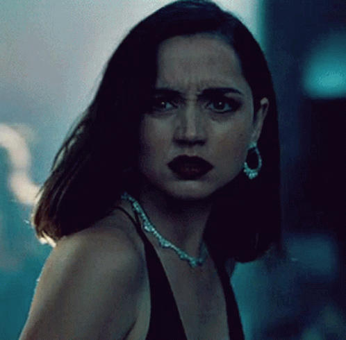 A Woman Wearing A Necklace And Earrings Looks At The Camera With A Serious Look On Her Face GIF