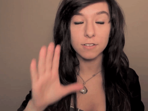 a woman wearing a necklace holds her hand up to her face