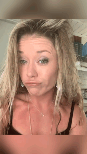 A Woman Wearing A Necklace With A Cross On It GIF