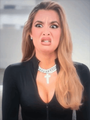 A Woman Wearing A Necklace With A Cross On It GIF