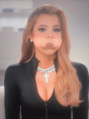 A Woman Wearing A Necklace With A Cross On It Makes A Funny Face GIF