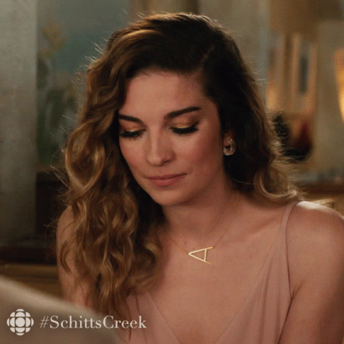 A Woman Wearing A Necklace With A Letter T On It GIF