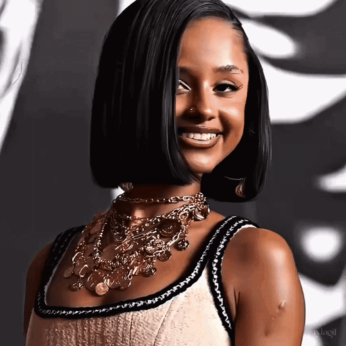 A Woman Wearing A Necklace With Coins On It Smiles For The Camera GIF