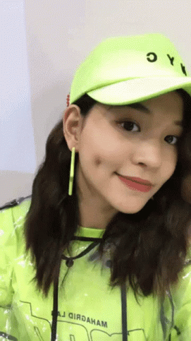 A Woman Wearing A Neon Green Hat And A Yellow Jacket GIF