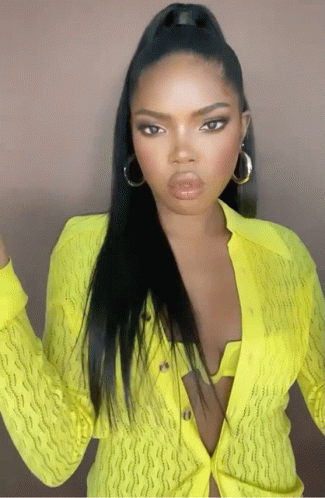A Woman Wearing A Neon Yellow Cardigan And Earrings GIF