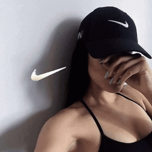 A Woman Wearing A Nike Hat Covering Her Face With Her Hand GIF