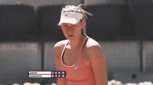 A Woman Wearing A Nike Visor And A Pink Tank Top Is Watching A Tennis Match Between Garcia And Sharapova GIF