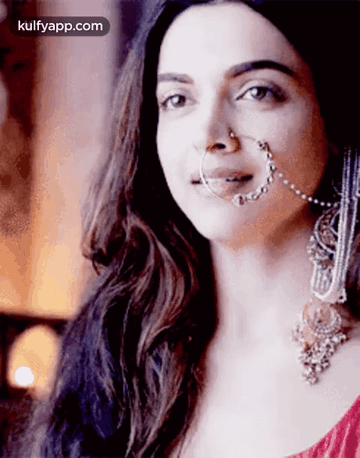 A Woman Wearing A Nose Ring And Earrings Is Looking At The Camera . GIF