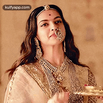 A Woman Wearing A Nose Ring Is Holding A Tray Of Food . GIF