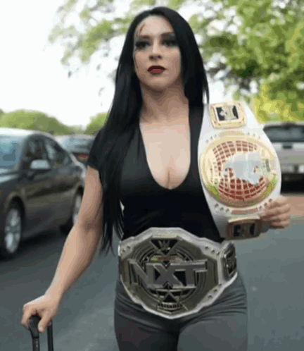 A Woman Wearing A Nxt Belt Is Walking Down A Street GIF