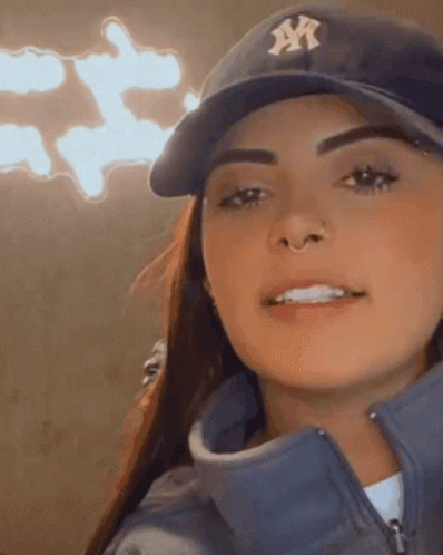 A Woman Wearing A Ny Yankees Hat And A Blue Jacket Is Smiling . GIF