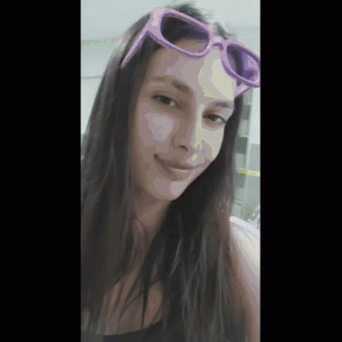 A Woman Wearing A Pair Of Pink Sunglasses Is Smiling GIF