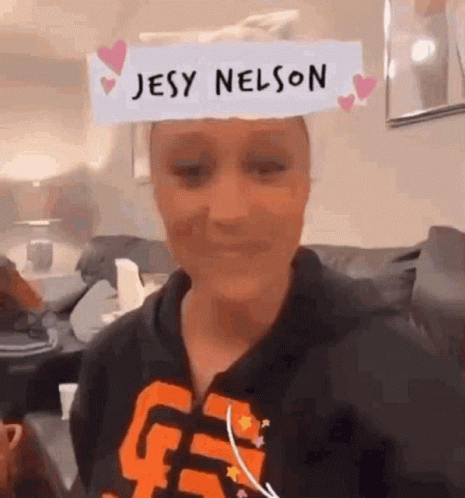 A Woman Wearing A Paper On Her Head That Says Jesy Nelson . GIF