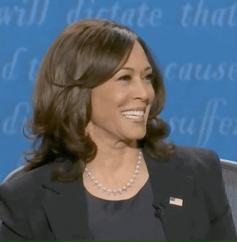 A Woman Wearing A Pearl Necklace And A Black Jacket Smiles GIF