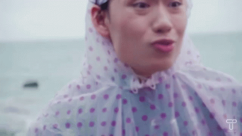 Woman In Pink And White Polka Dot Raincoat By Ocean GIF