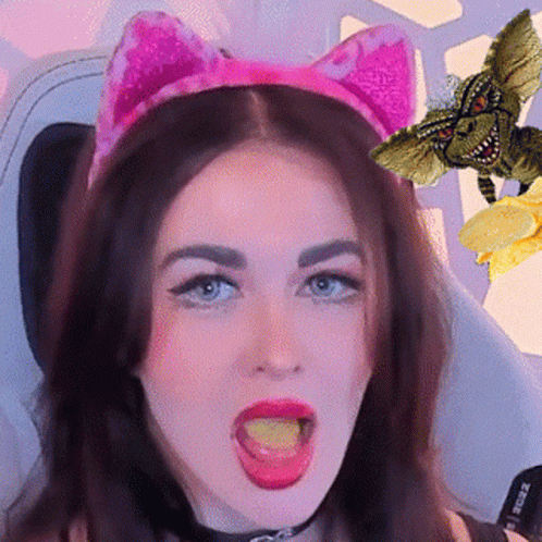 A Woman Wearing A Pink Cat Ear Headband Is Eating A Piece Of Cheese GIF