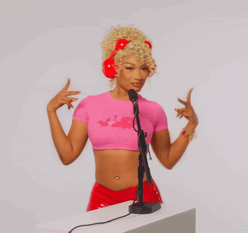 a woman wearing a pink crop top and red headphones is standing in front of a microphone