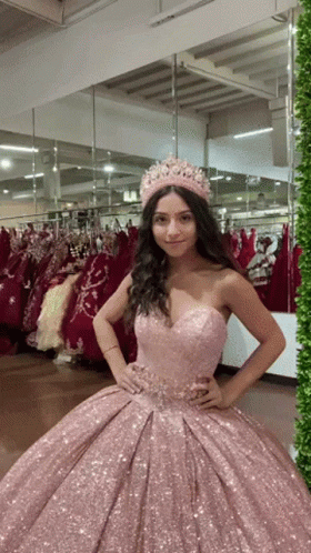A Woman Wearing A Pink Dress And A Crown Is Standing In Front Of A Mirror GIF