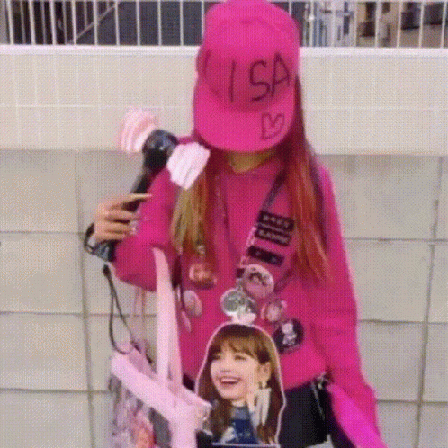 A Woman Wearing A Pink Hat And A Pink Sweater Is Holding A Microphone And A Backpack . GIF