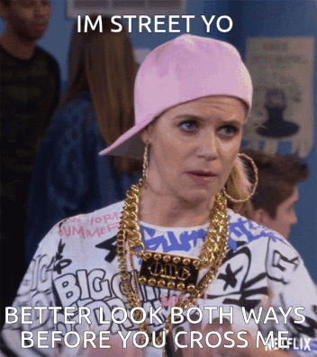 A Woman Wearing A Pink Hat And Gold Chains Says " Im Street Yo Better Look Both Ways Before You Cross Me " GIF