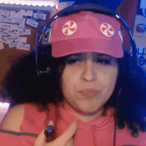 A Woman Wearing A Pink Hat And Headphones Is Holding Something GIF