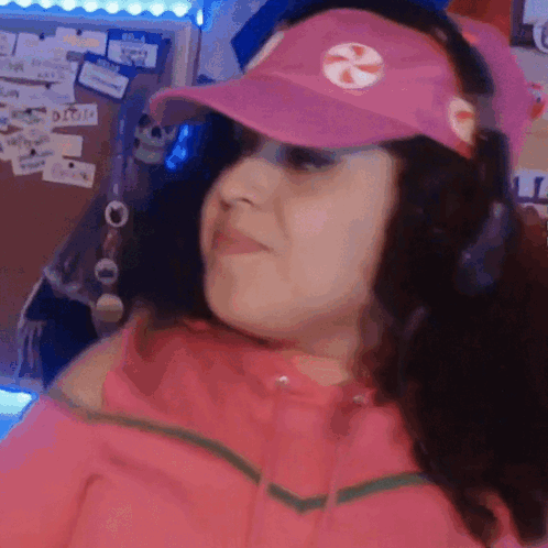 A Woman Wearing A Pink Hat And Headphones Is Making A Funny Face . GIF