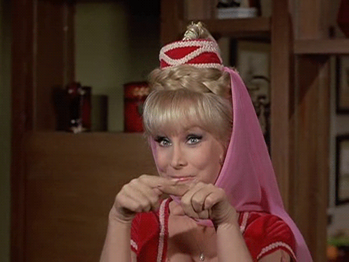 A Woman Wearing A Pink Head Scarf And A Red Top Is Making A Funny Face . GIF