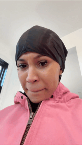 A Woman Wearing A Pink Jacket And A Black Hat Is Making A Sad Face GIF