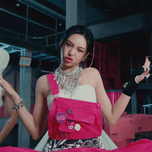 A Woman Wearing A Pink Overalls And A Necklace With A Button That Says Adb GIF