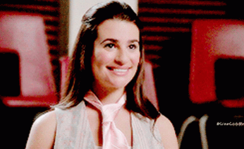 A Woman Wearing A Pink Tie Is Smiling And Looking At The Camera GIF