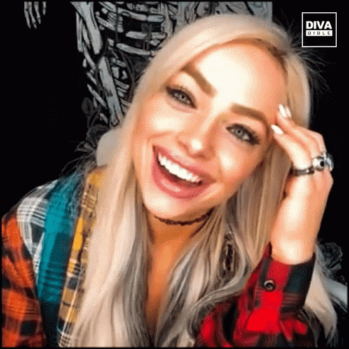 A Woman Wearing A Plaid Shirt And A Ring Is Smiling For A Diva Photo GIF