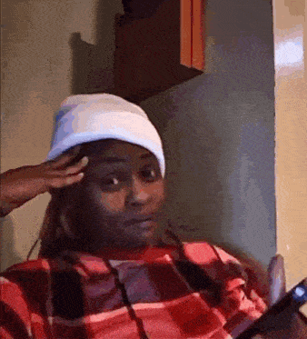 a woman wearing a plaid shirt and a white hat looks at her phone