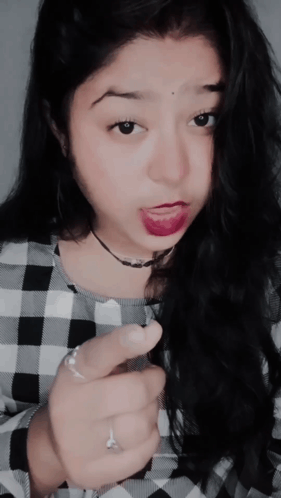 A Woman Wearing A Plaid Shirt Is Making A Face GIF