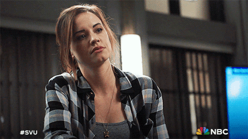 A Woman Wearing A Plaid Shirt Is Sitting In Front Of A Nbc Logo GIF