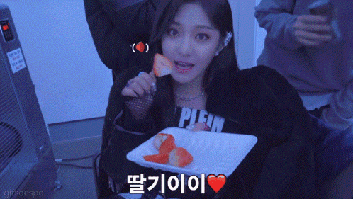 a woman wearing a plein sweatshirt eating strawberries