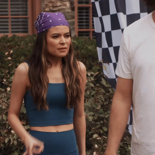 A Woman Wearing A Purple Bandana Stands Next To A Man In Front Of A Checkered Flag GIF
