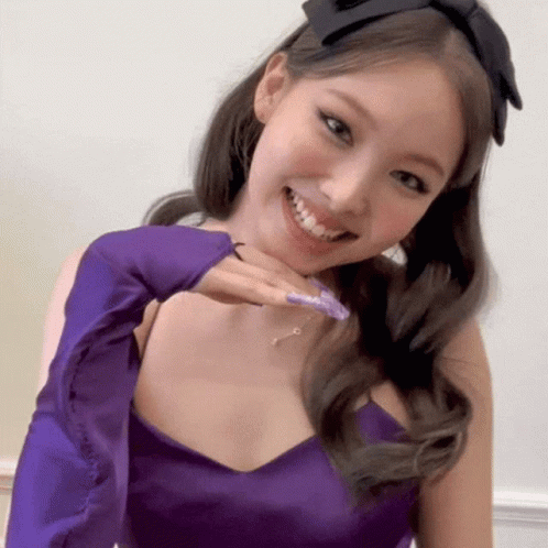 A Woman Wearing A Purple Dress And A Headband Is Smiling GIF