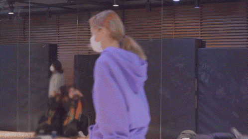 a woman wearing a purple hoodie and a bandana is standing in a room .