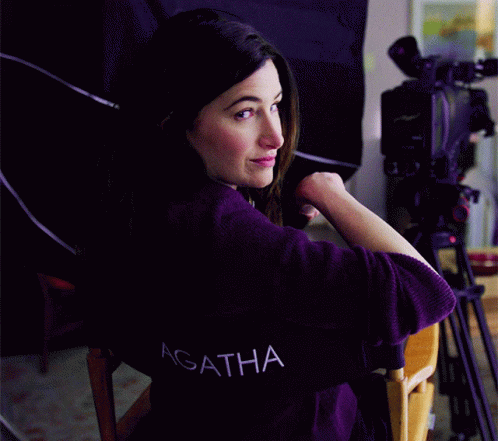 A Woman Wearing A Purple Shirt With The Word Agatha On The Back GIF