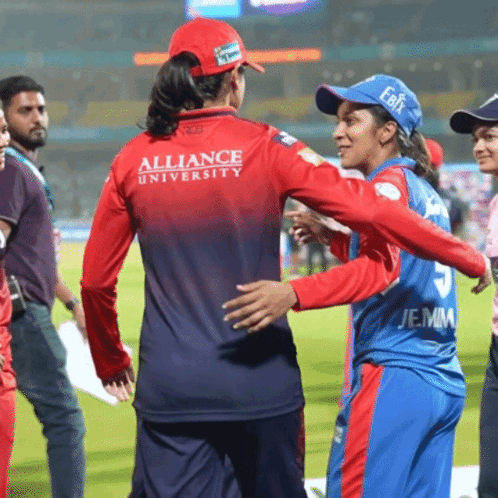A Woman Wearing A Red Alliance University Jersey Is Hugging Another Woman GIF