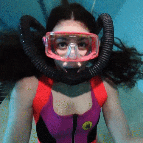 A Woman Wearing A Red And Purple Swimsuit Is Swimming GIF