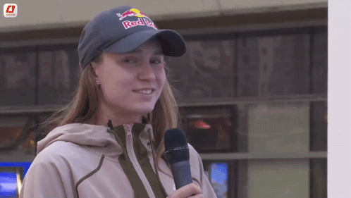A Woman Wearing A Red Bull Hat Holds A Microphone In Her Hand GIF