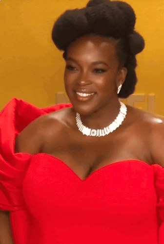 A Woman Wearing A Red Dress And A White Necklace With The Letter I On It GIF