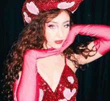 A Woman Wearing A Red Dress And Pink Gloves With Hearts On Them GIF