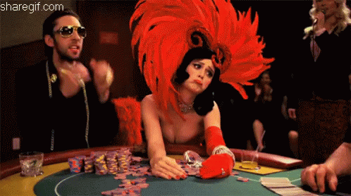 A Woman Wearing A Red Feathered Headdress Is Playing Poker GIF